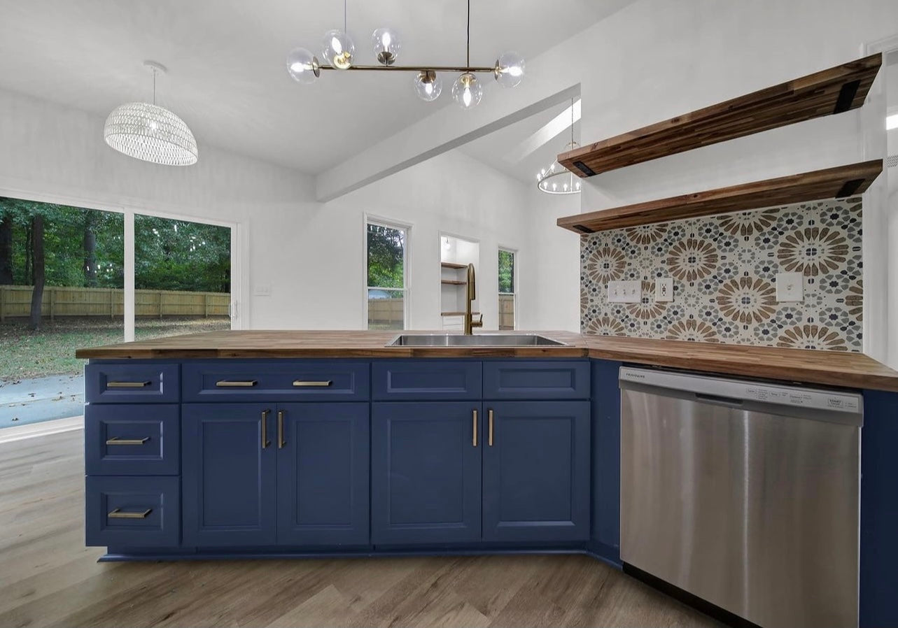 Blue kitchen cabinets with wood countertops, patterned backsplash, and stainless steel appliances