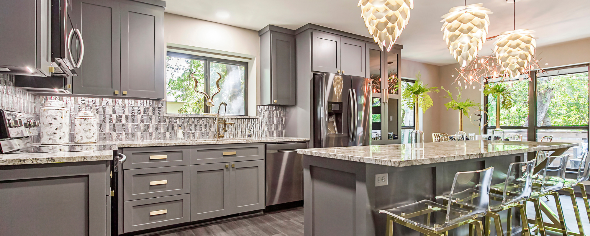 Modern gray shaker kitchen cabinets with marble countertops, stainless steel appliances, and pendant lighting