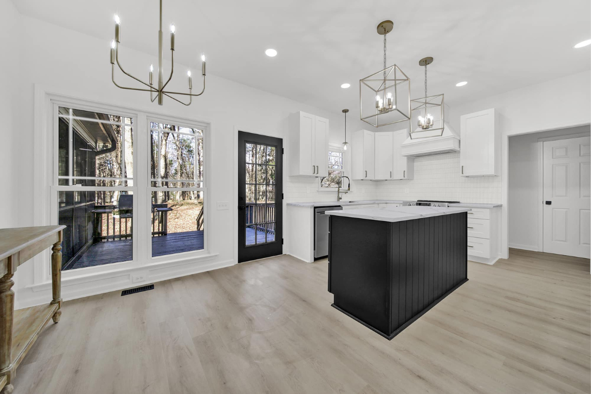 Modern kitchen with white shaker cabinets, black island, and light wood flooring
